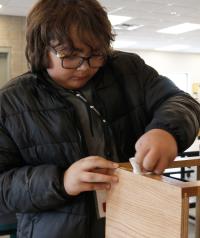 A Kids Switch participant learns how to install hinges on a cabinet door.