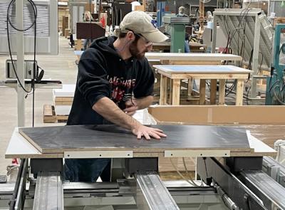 An operator lays up a wood component for one of the company’s residential furniture products. The multi-axis Morbidelli is a pod-and-rail system that allows access to most of the board, including the top and sides.